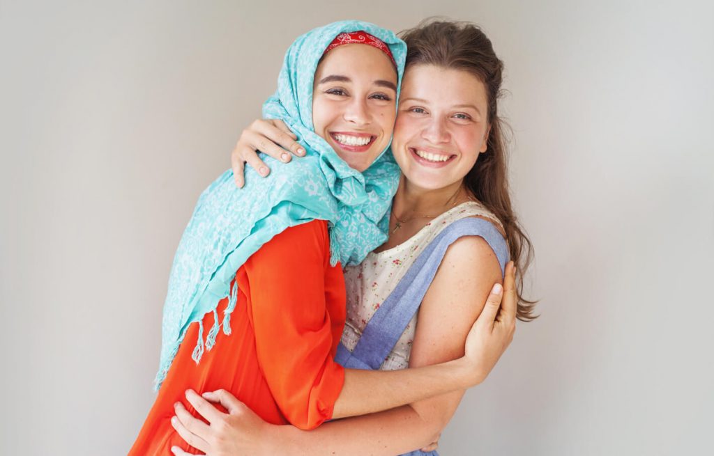 Muslim and christian girl friendly hug
