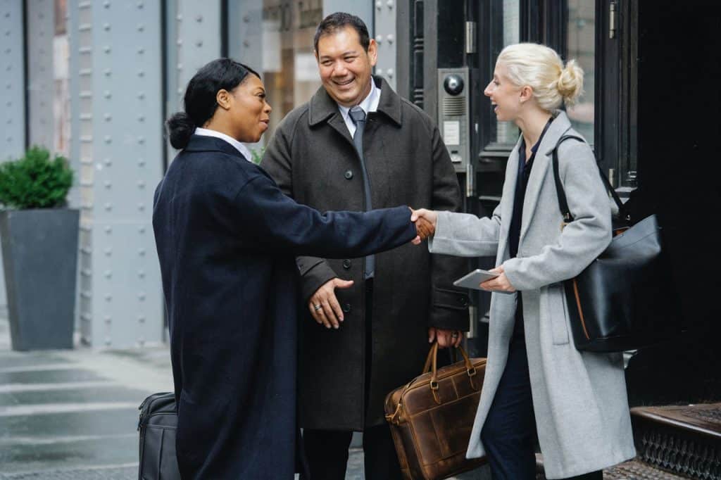 A group of three people shaking hands on the street