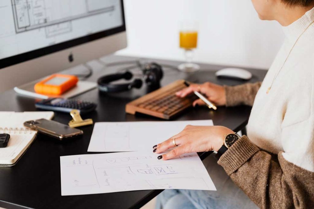 Woman in front of computer screen editing documents