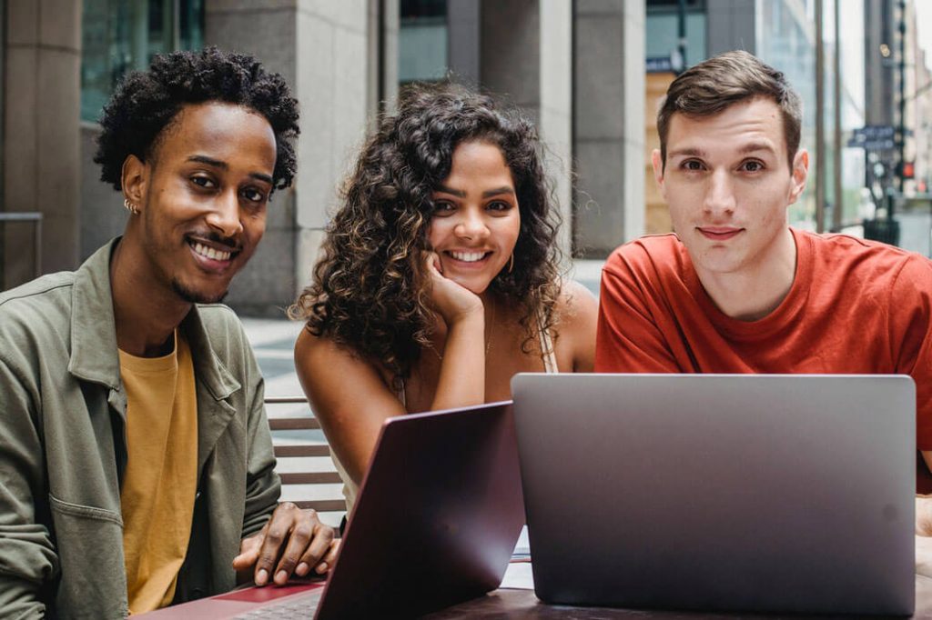 three multinational students smiling and sitting at their desks