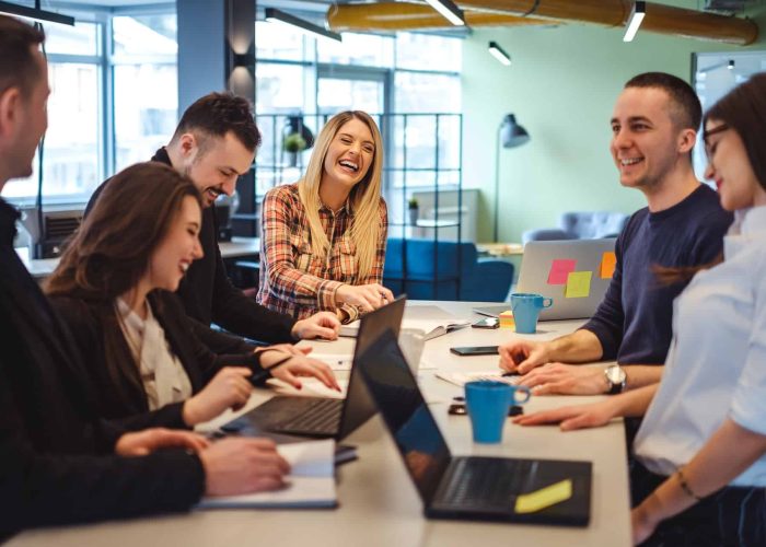 Happy colleagues laughing in the office at the meeting table