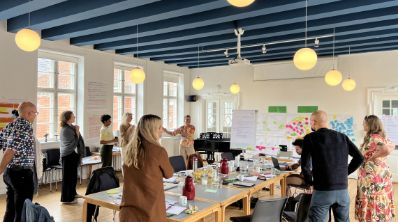 people standing inside a bright room having a meeting