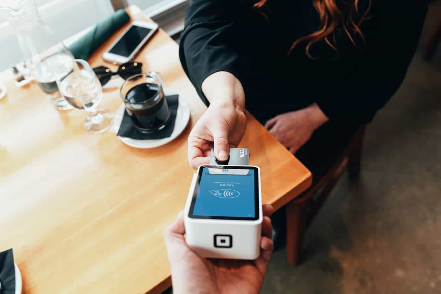 Person paying at a credit card terminal in a café