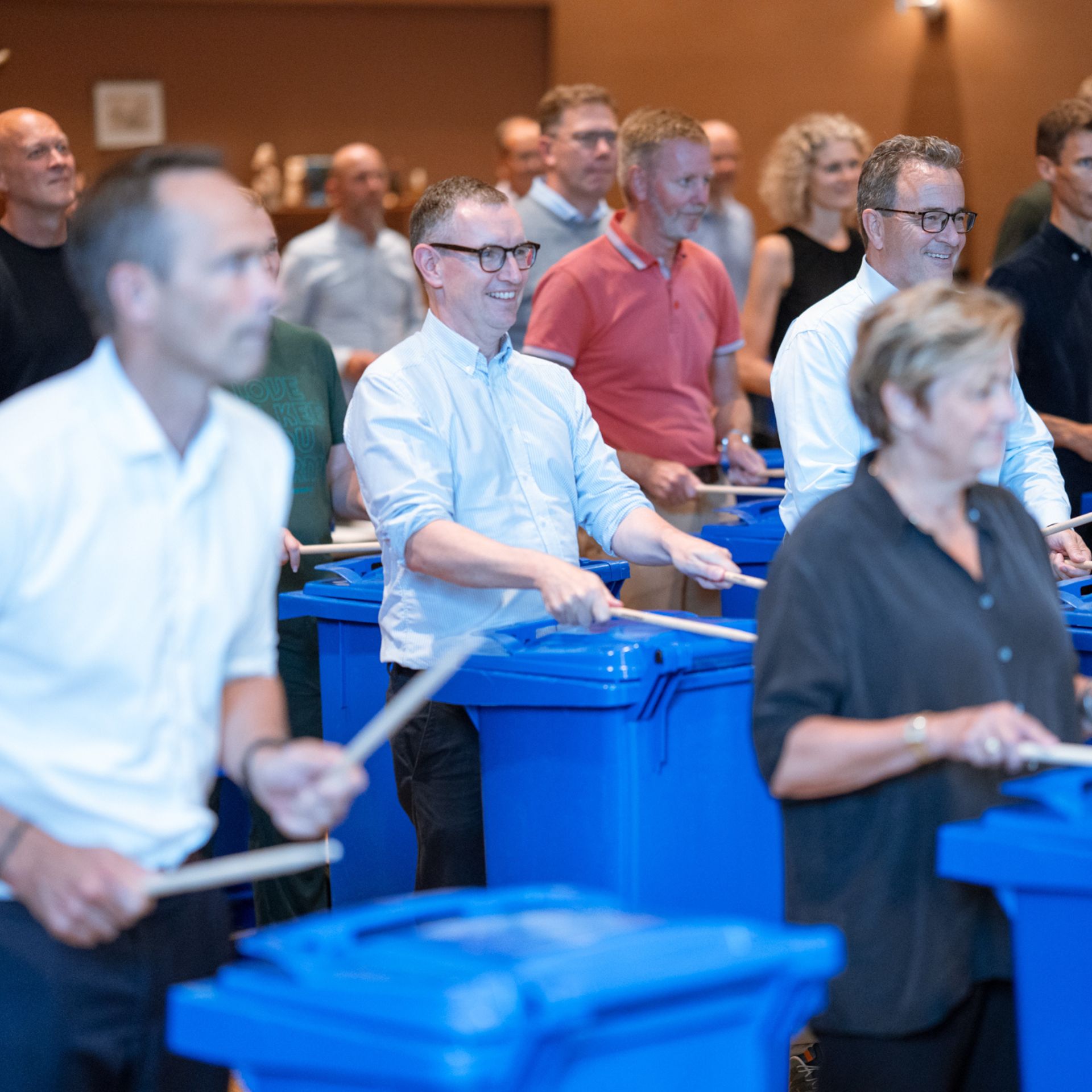 Die Kopenhagen Trommler veranstalten Teambuilding mit einem Unternehmen, bei dem die Teilnehmer mit Trommelstöcken auf Mülleimer schlagen.