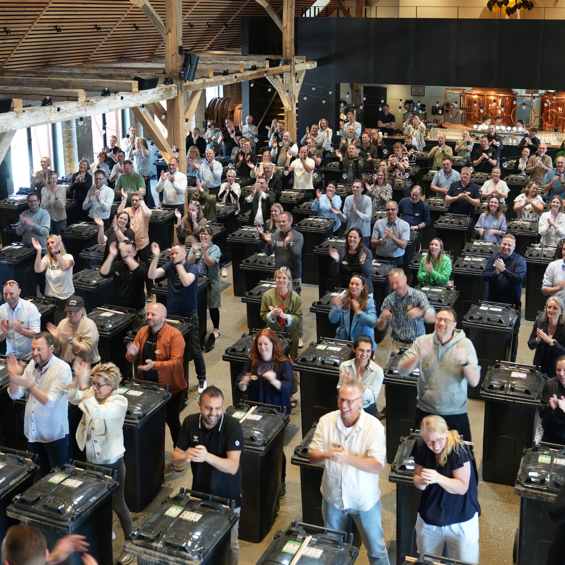 Die Kopenhagen Trommler veranstalten Teambuilding mit einem Unternehmen, bei dem die Teilnehmer mit Trommelstöcken auf Mülleimer schlagen.