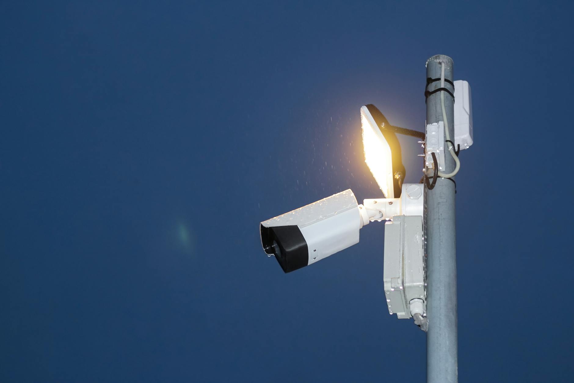 surveillance camera and illuminated light under a blue sky