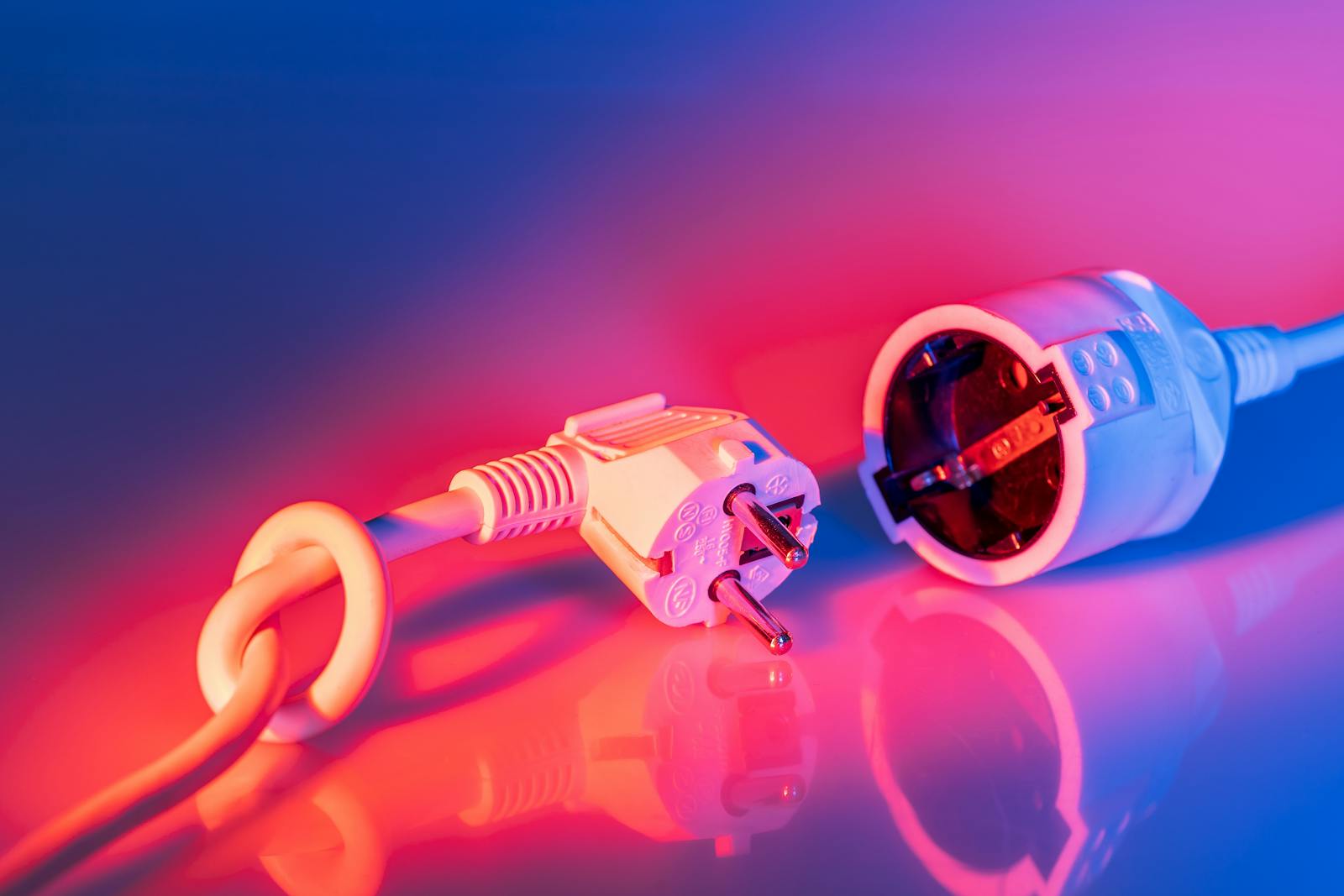 Close-up of electric plug and socket with vibrant lighting, showcasing technology and energy concepts.