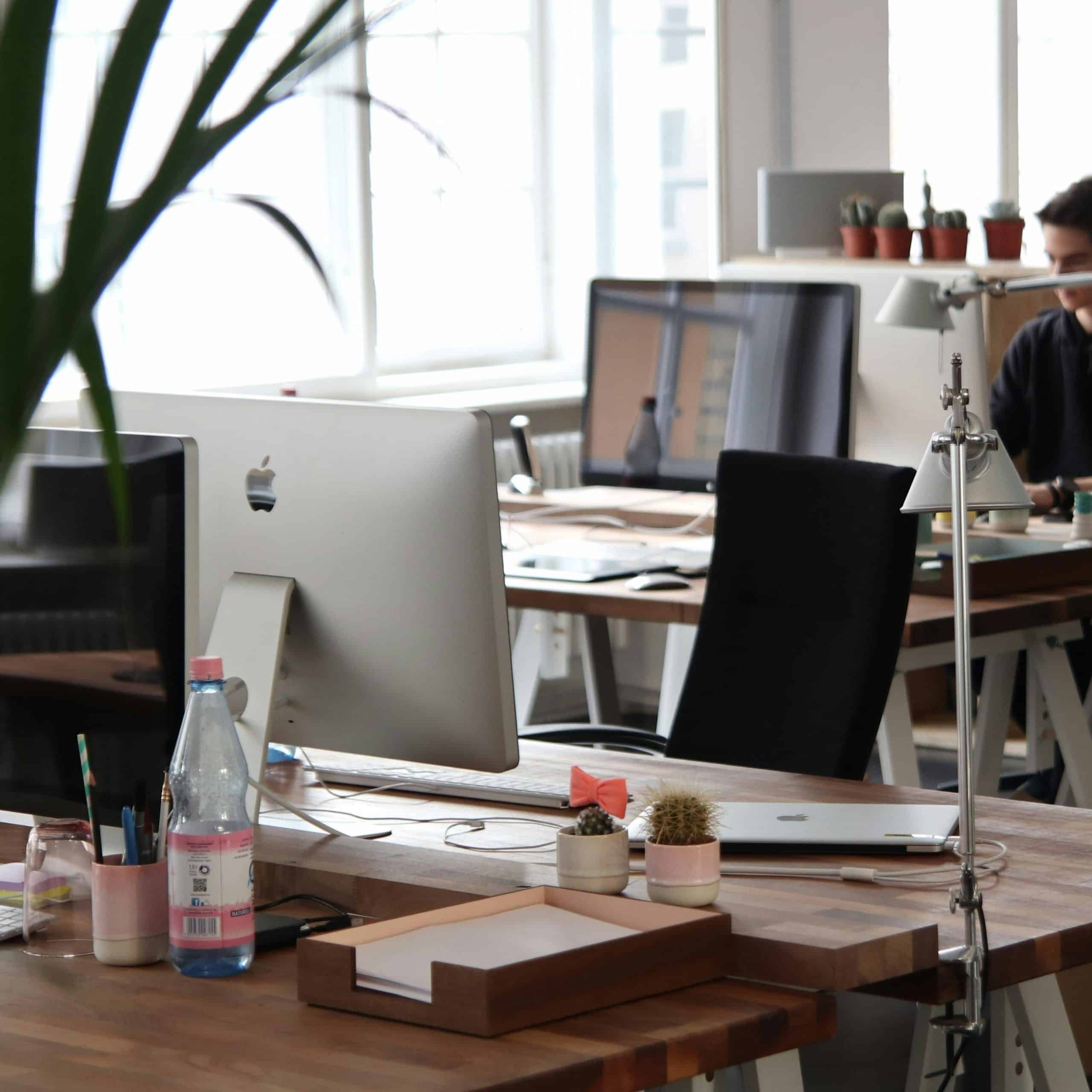 Image of an office space, with tables with computers and personal things on the tables