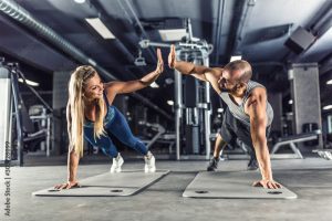 Sport couple doing plank exercise workout in fitness centrum. Man and woman practicing plank in the gym
