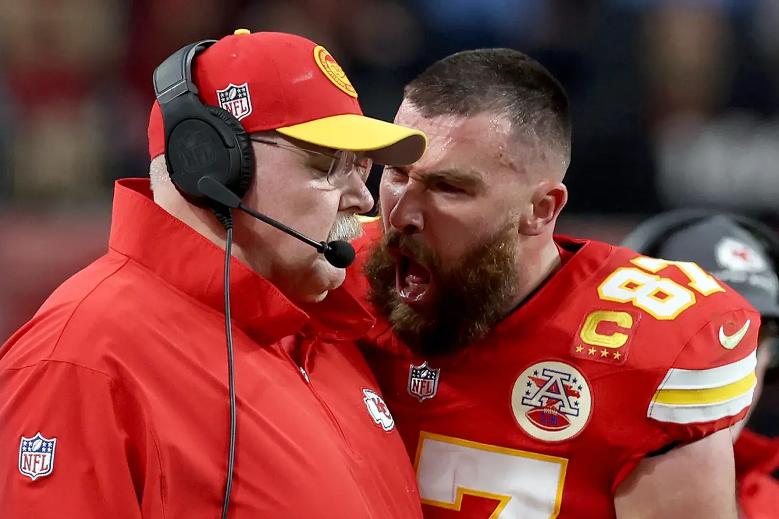 Kansas City Chiefs football player in animated discussion with coach during NFL game.