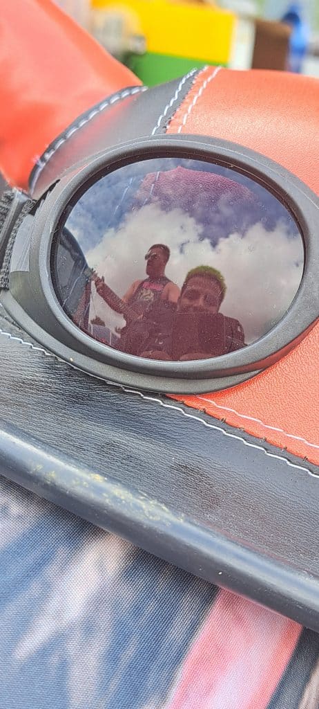 Two men reflected in a goggle lens.