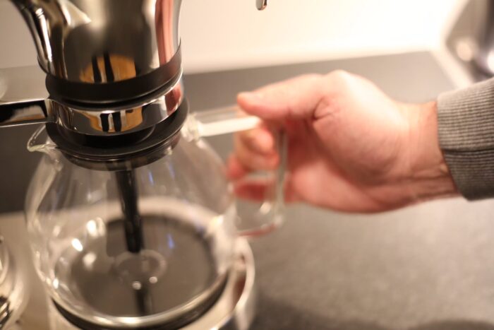 En hand håller i den tomma glaskannan till Aarke Coffee Maker