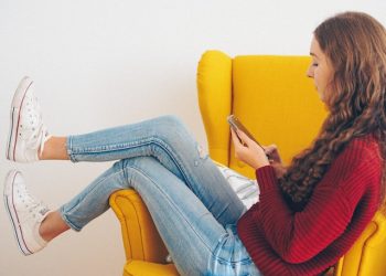 Vem ringde? Kvinna undersöker telefonnummer i fåtölj.