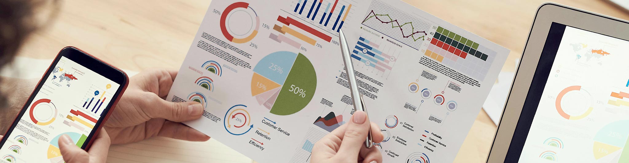 Skrivbord med utskrifter, telefon med SoMe och skärm med videopresentation.