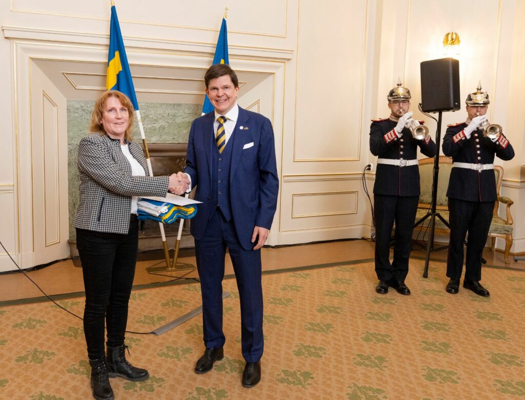 Riksdagens talman Andreas Norlén överlämnar den svenska flaggan till dalakretsens ordförande Lena Sjögren den 10:e mars 2022.
