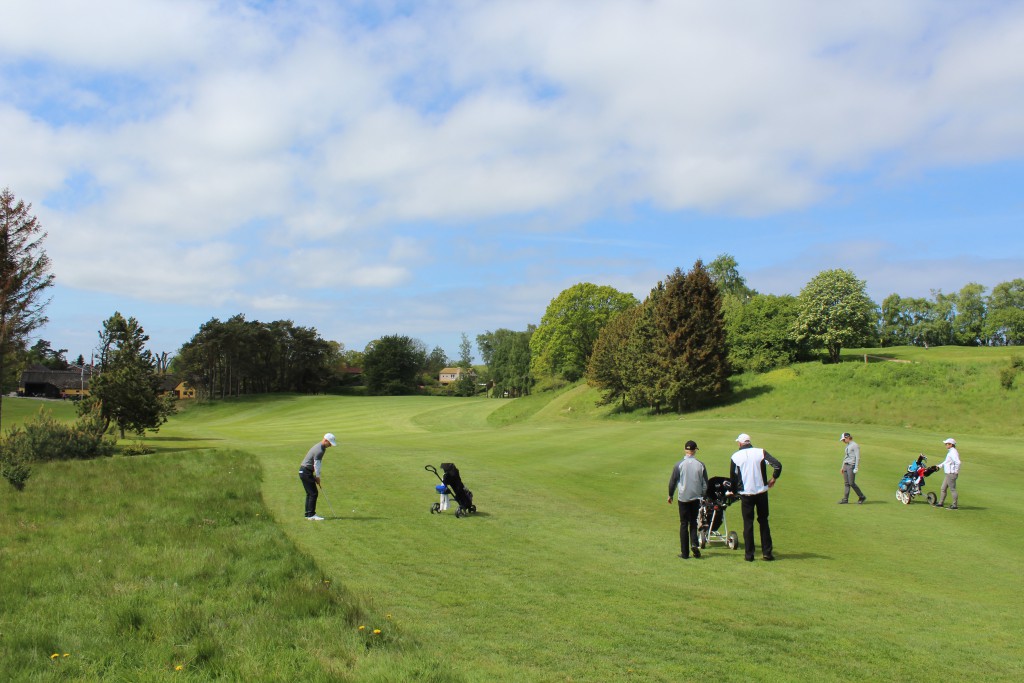 HUL 18, par 5. Spillerne ligger i deres første slag. Foberedels til slag med kølle mod en bakkersom ligger ca. 50-75 m foran green. Foto den 24. maj 2015 af Erik K Abrahamsen