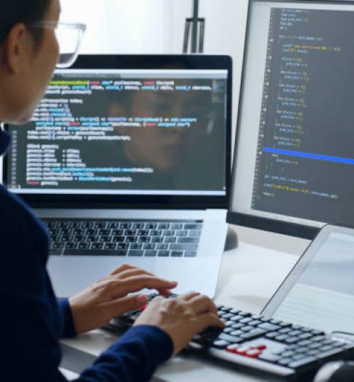 Young Asian woman, developer programmer, software engineer, IT support, wearing glasses working on computer to check coding in bugging system. Back view