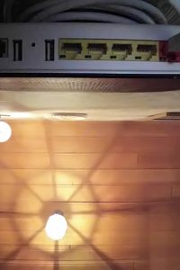 När man ser Routern underifrån framgår det att LAN-kabeln är "undangömd" bakom Routern och hänger över samma två skruvar som håller Routern på väggen. Installation av Telia Internet router och anslutning till fiberoptikdosan hos en kund på Djursholm.