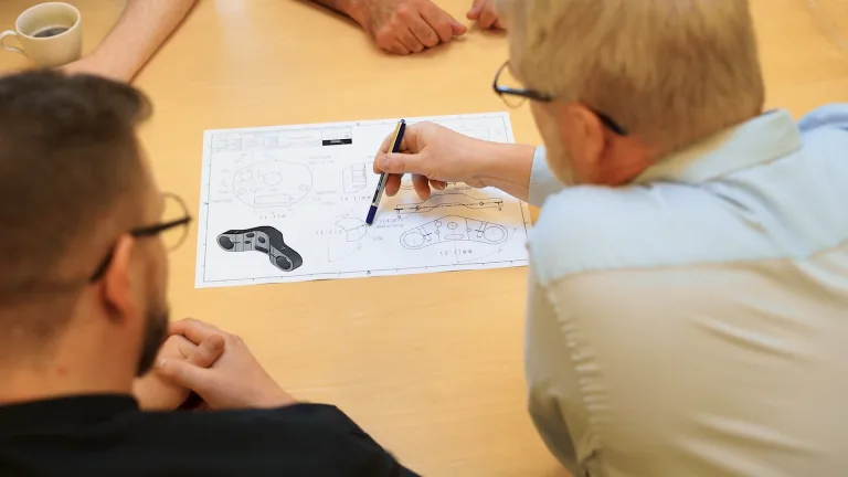 To mænd, der sidder og kigger på et papir med udvikling af produkt