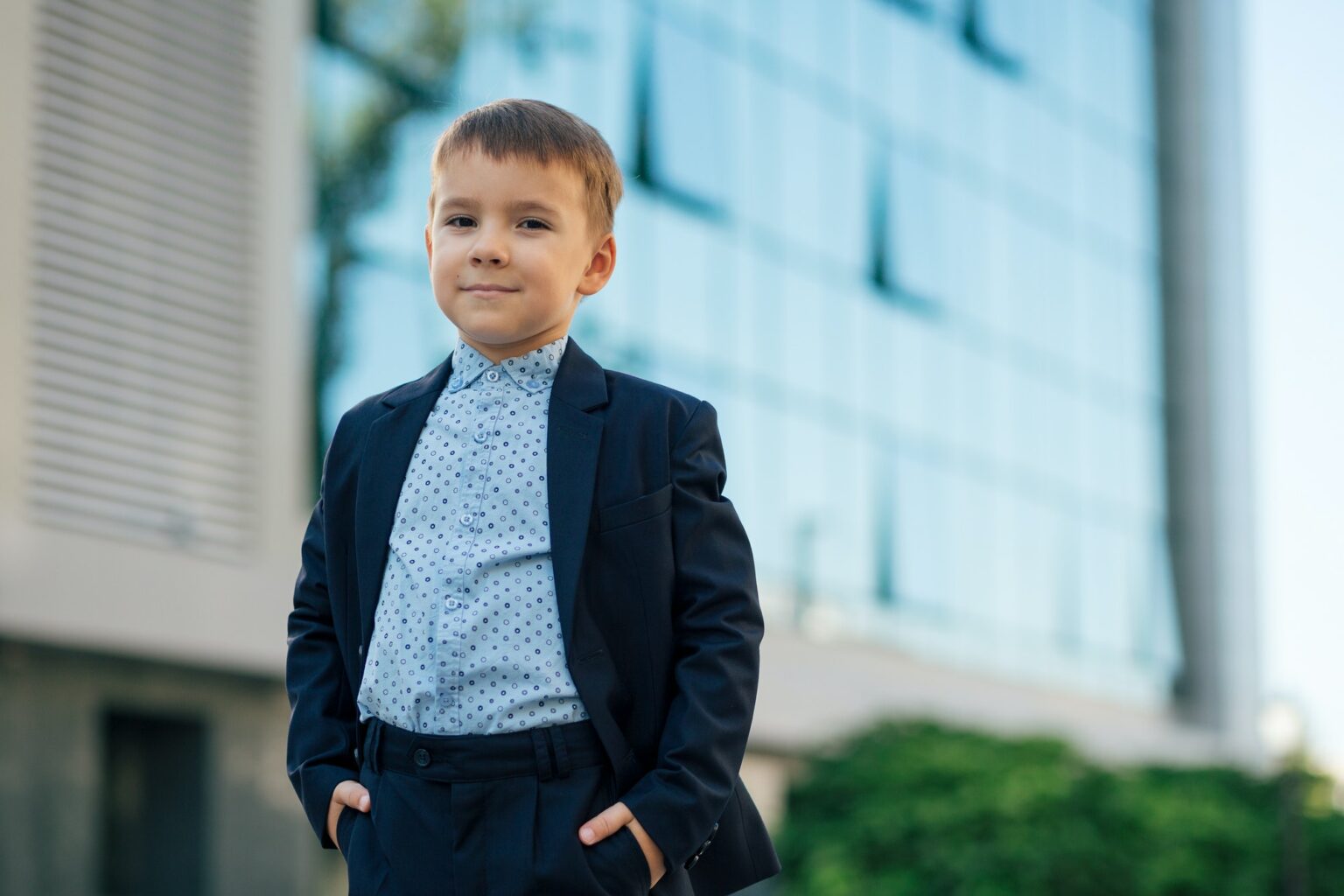Boy in classic dark blue business costume with arms in pockets