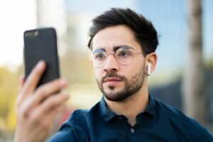 Young man using face id for unlock mobile phone outdoors.