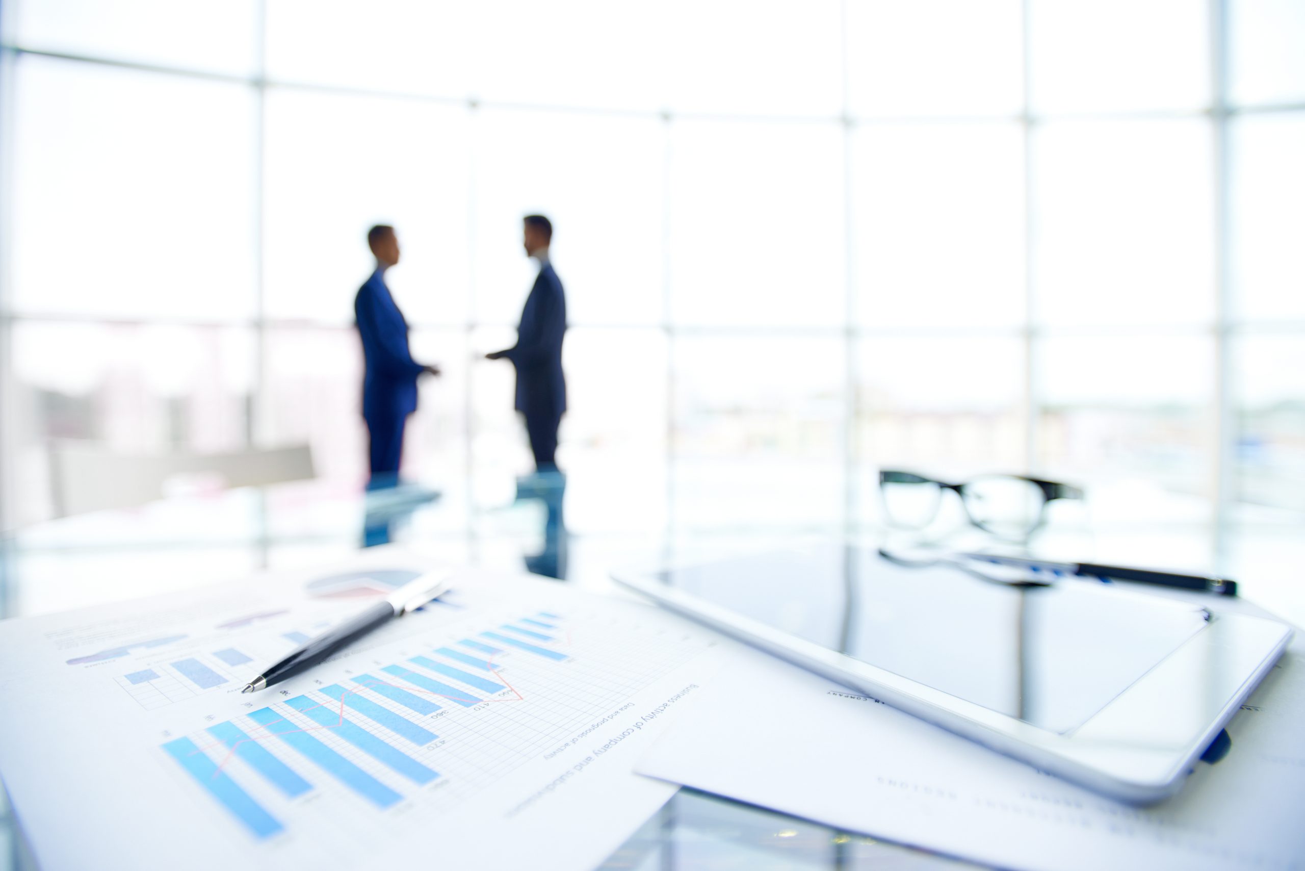 Close-up of business objects at workplace on background of office workers interacting