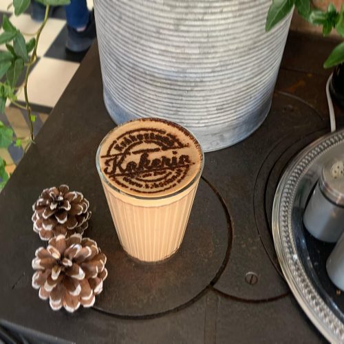 Cappucino serverad kakao sprinklat i caféets logotyp