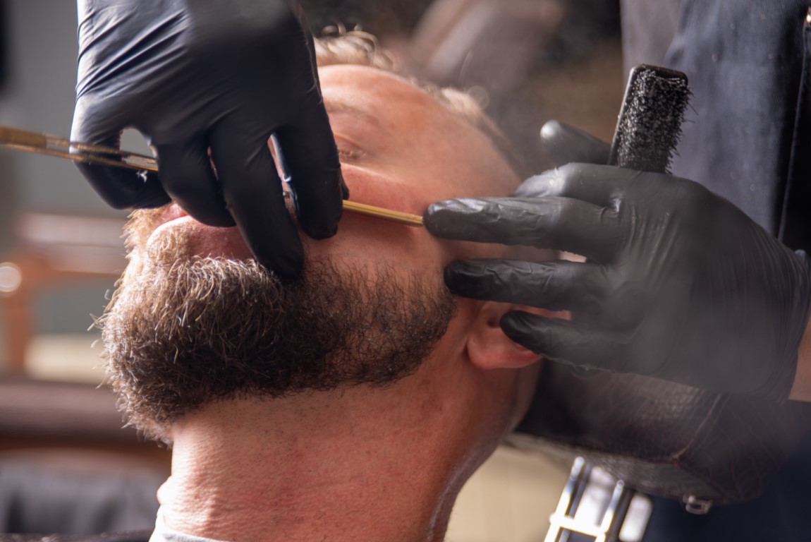 Barber shop, barber shaving his client, selective focus.
