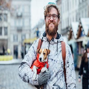 Ein Mann im Winter mit seinem Hund auf dem Arm auf einem Hundeweihnachtsmarkt.