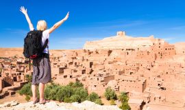 traveler arms reised in front of ait benhaddou morocco