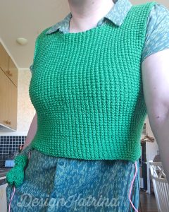 Copyright: DesignKatrina.se
Work in progress, Nightingale Pullover. 
*Womn standing with a half finished green sweater without sleeves and a dress underneath*. 