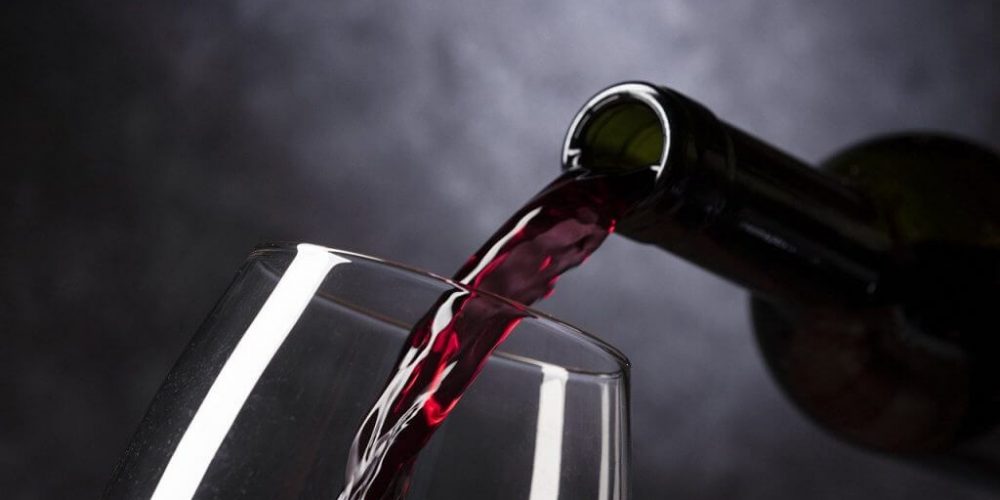 Alkohol kultur i Danmark Alkoholisme, Alkoholafhængighed & Alkoholmisbrug - Viser rødvin der hældes ud af flasken, ned i et vin glas