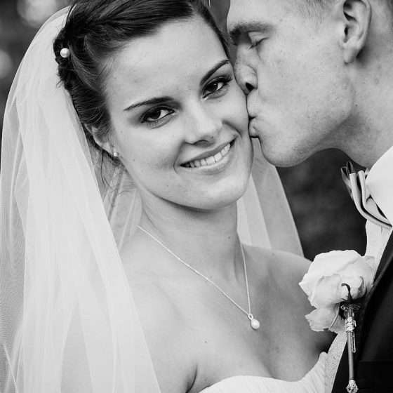 bryllupsfotografering bryllupsbillede brud kysses på kinden af gom