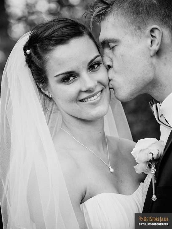 bryllupsfotografering bryllupsbillede brud kysses på kinden af gom