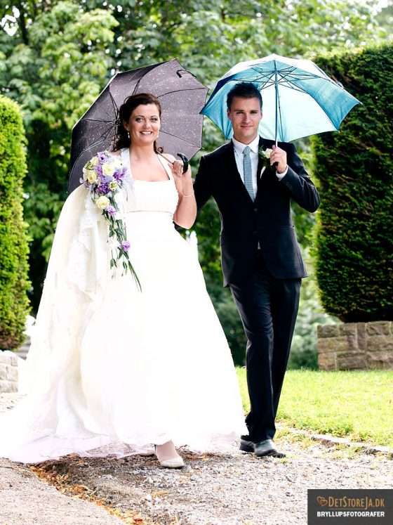 bryllupsbillede gående brudepar med paraplyer