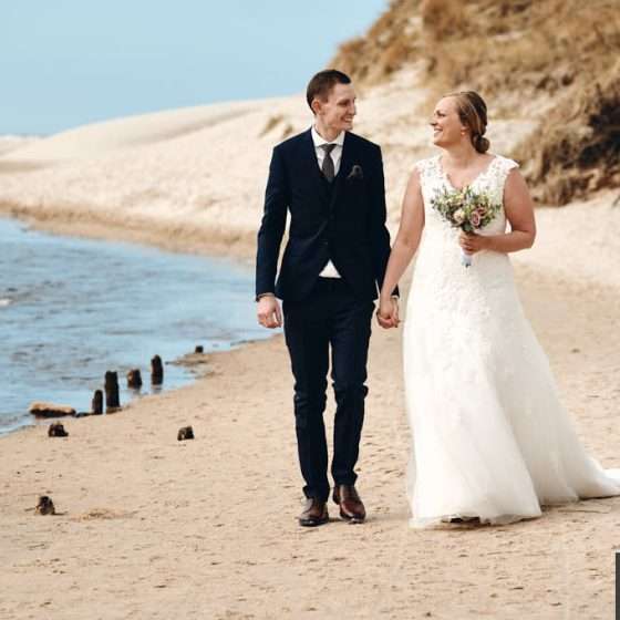 Brud og gom går på stranden ved Vesterhavet.