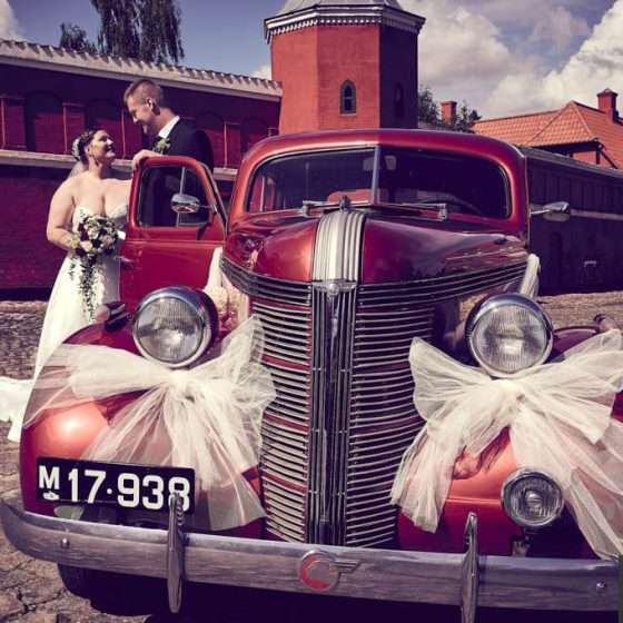Bryllupsportræt med brudepar fra Fyn og deres røde veteranbil