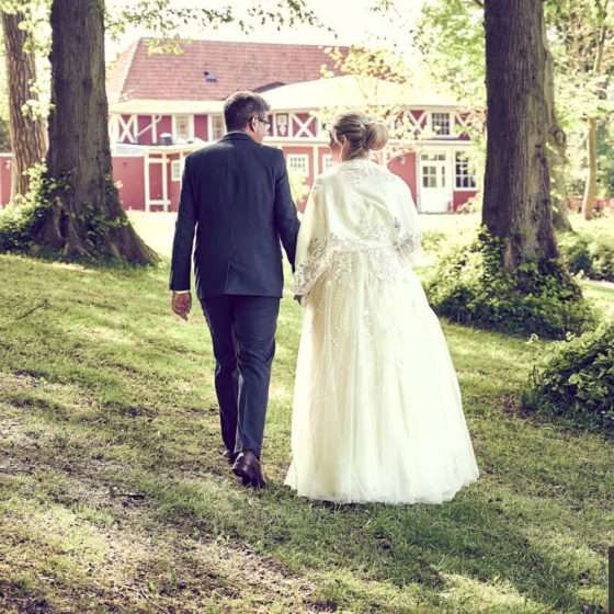 Bryllupsmed gom og brud gående sammen mellem træerne i Assens på Fyn