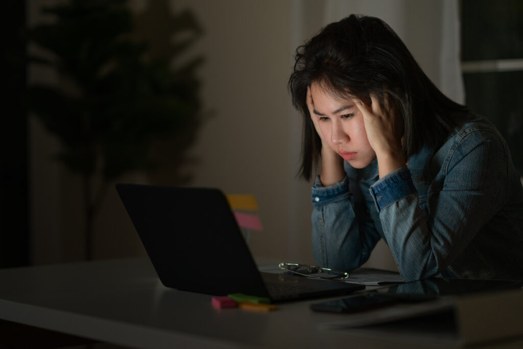 Vrouw zit met een burn-out naar haar scherm te staren