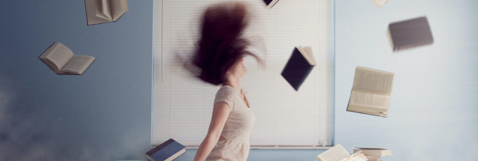 Een perfectionistische vrouw zit gestresseerd op haar bed, smijt boeken in de lucht en haar haren naar achter