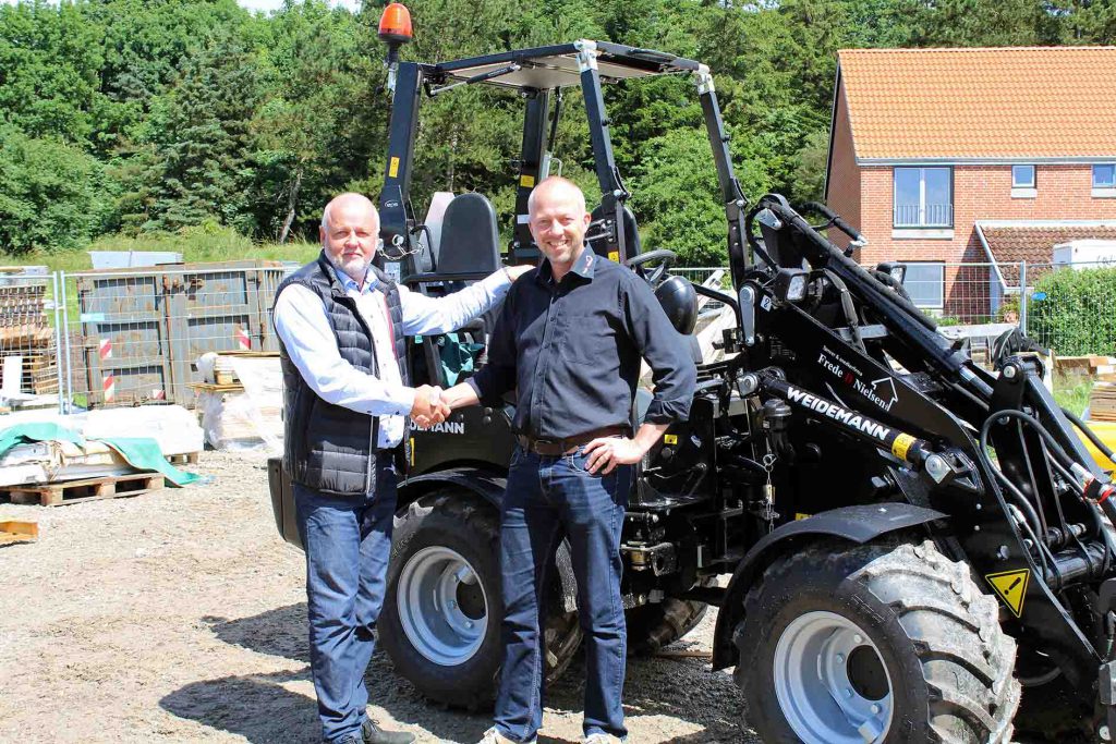 Stemas har leveret den nye Weidemann 1350 CX45 til TÃ¸mrer- og Snedkerfirmaet Frede D. Nielsen. Salgschef Robert KjÃ¦rgaard (til venstre) og tÃ¸mrermester Peter Berg-Mortensen giver hÃ¥nd pÃ¥ handelen med den sorte maskine.