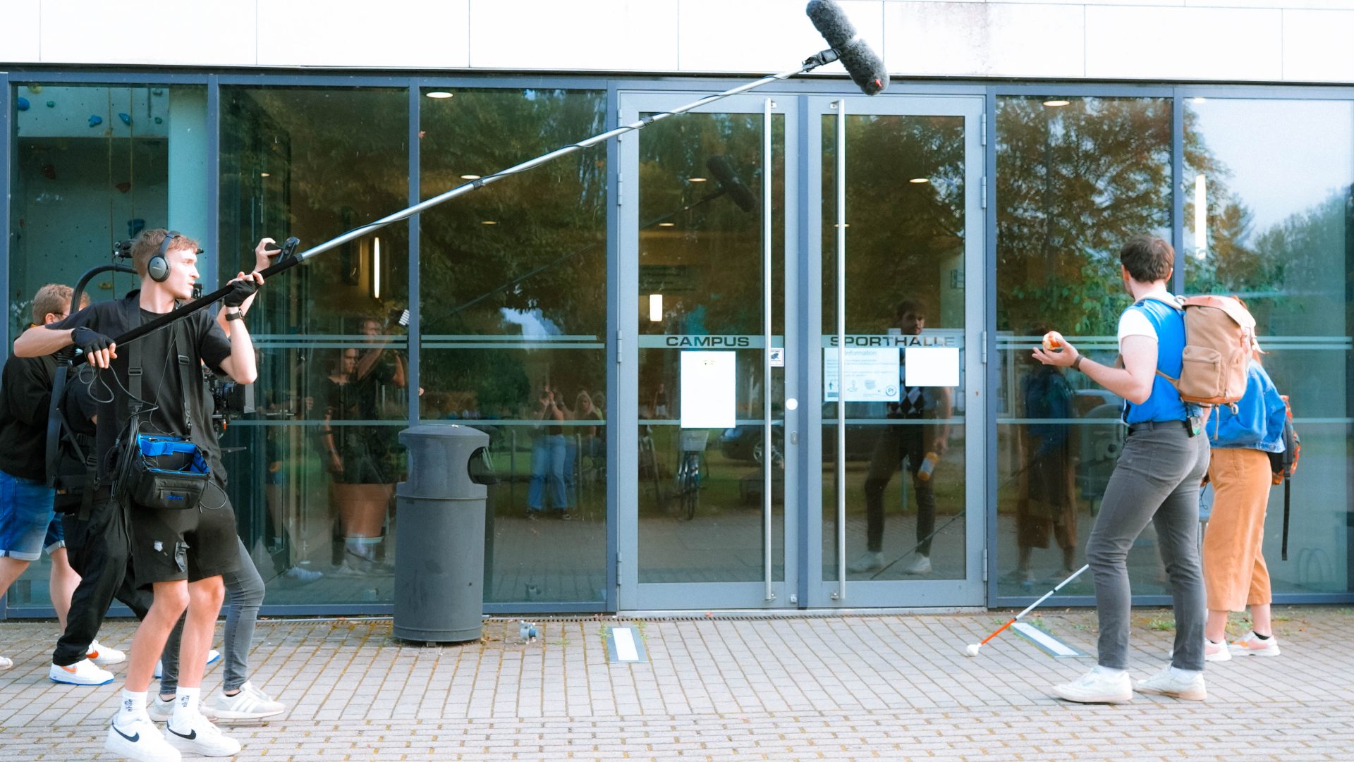 Filmcrew beim Dreh vor der Sporthalle. Andrew und Sara vor der Kamera