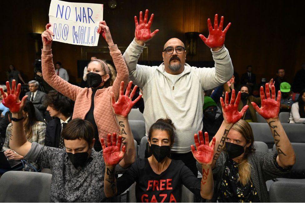 Protesters raise red painted hands as US Secretary of State Antony Blinken and Defense Secretary Lloyd Austin testify during a Senate Appropriations Committee hearing on a funding request for Israel