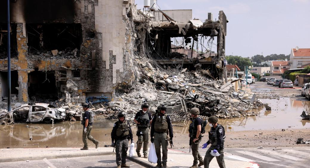 İsrail güvenliği, Hamas teröristlerinin Gazze Şeridi'nden güney İsrail'in Sderot kentine kitlesel sızmasının ardından çatışma alanında bir tüfeğin yanında toplandı 8 Ekim 2023 (fotoğraf kaynak: RONEN ZVULUN/REUTERS)