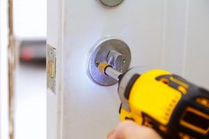 Closeup of a professional locksmith installing a new lock on a house exterior door with the inside