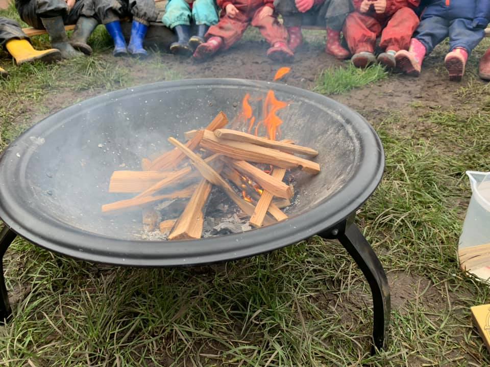 A fire pit with the children sat around