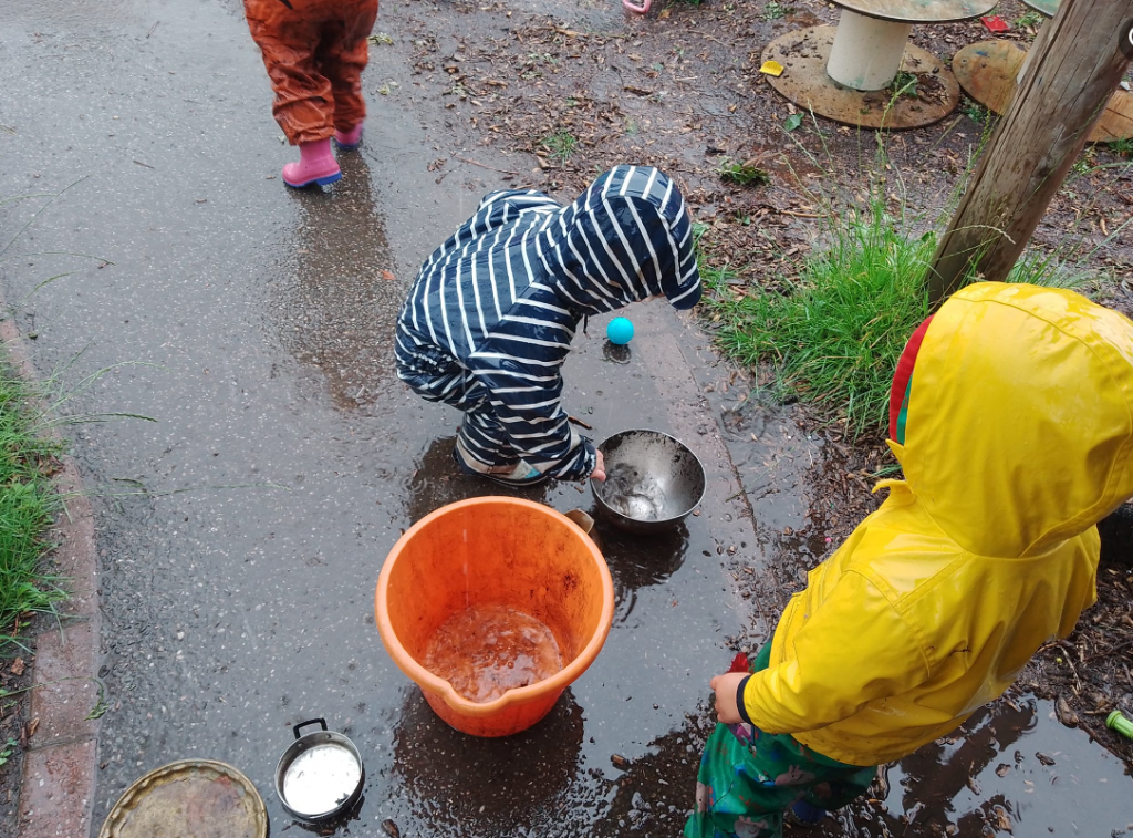 Children collecting rain water in buckets at pre-school