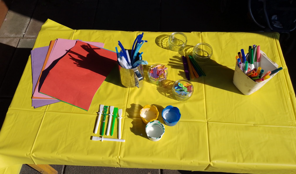 A table set up with paints and glue and coloured card