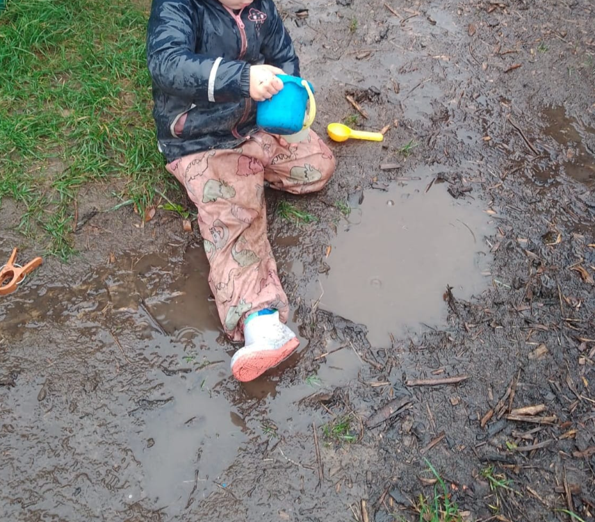 A child sitting in the mud playing