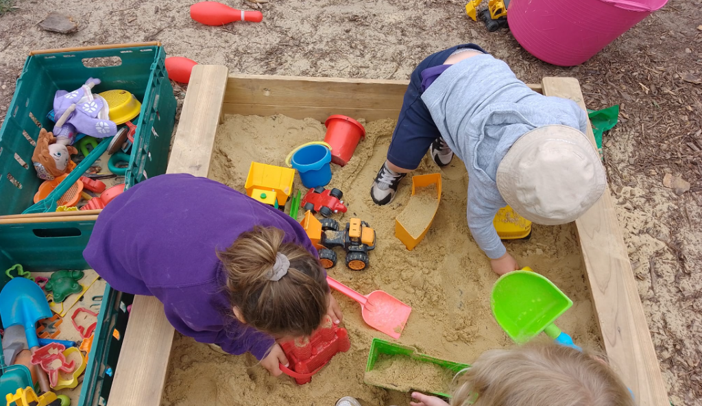 2 children playing with spaces in a sandpit